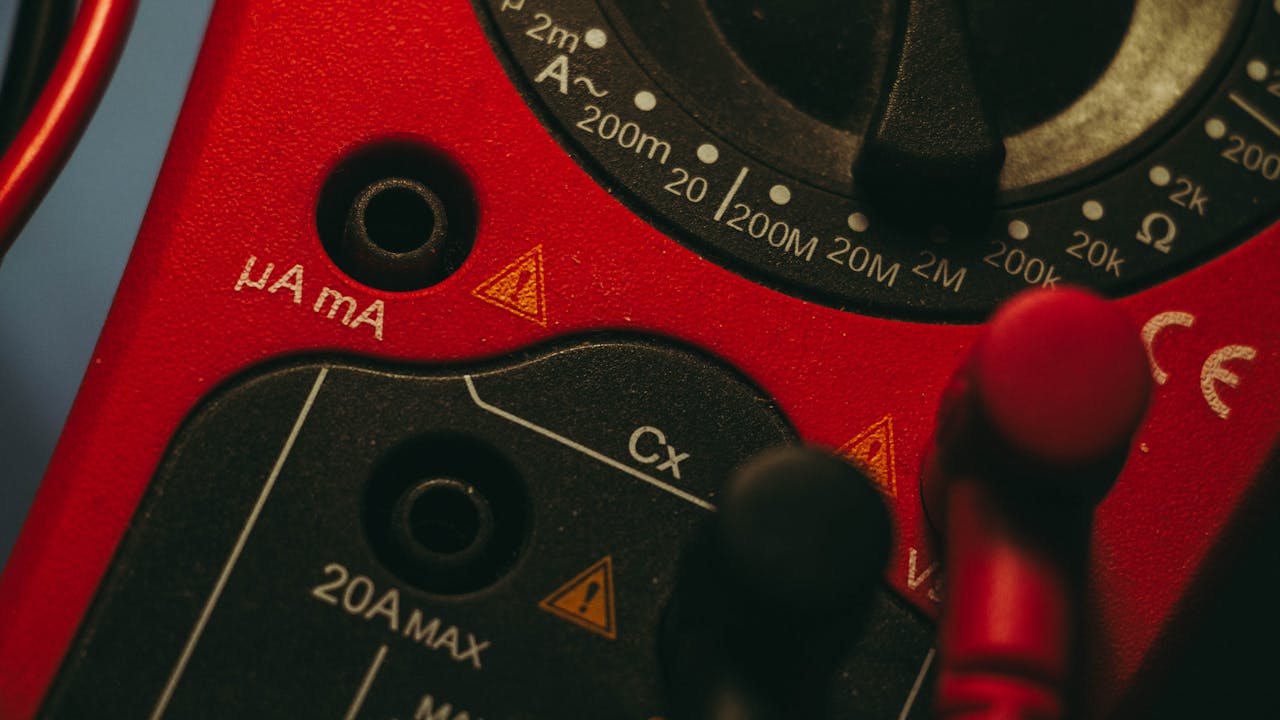 Detailed image of a red multimeter, showcasing measurement dial and connectors, ideal for tech enthusiasts.
